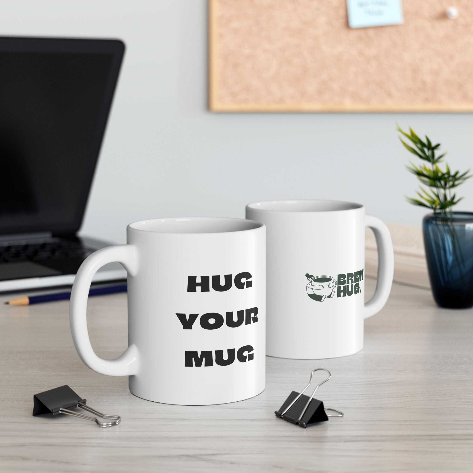 Two white mugs with humorous text on a desk with office supplies.