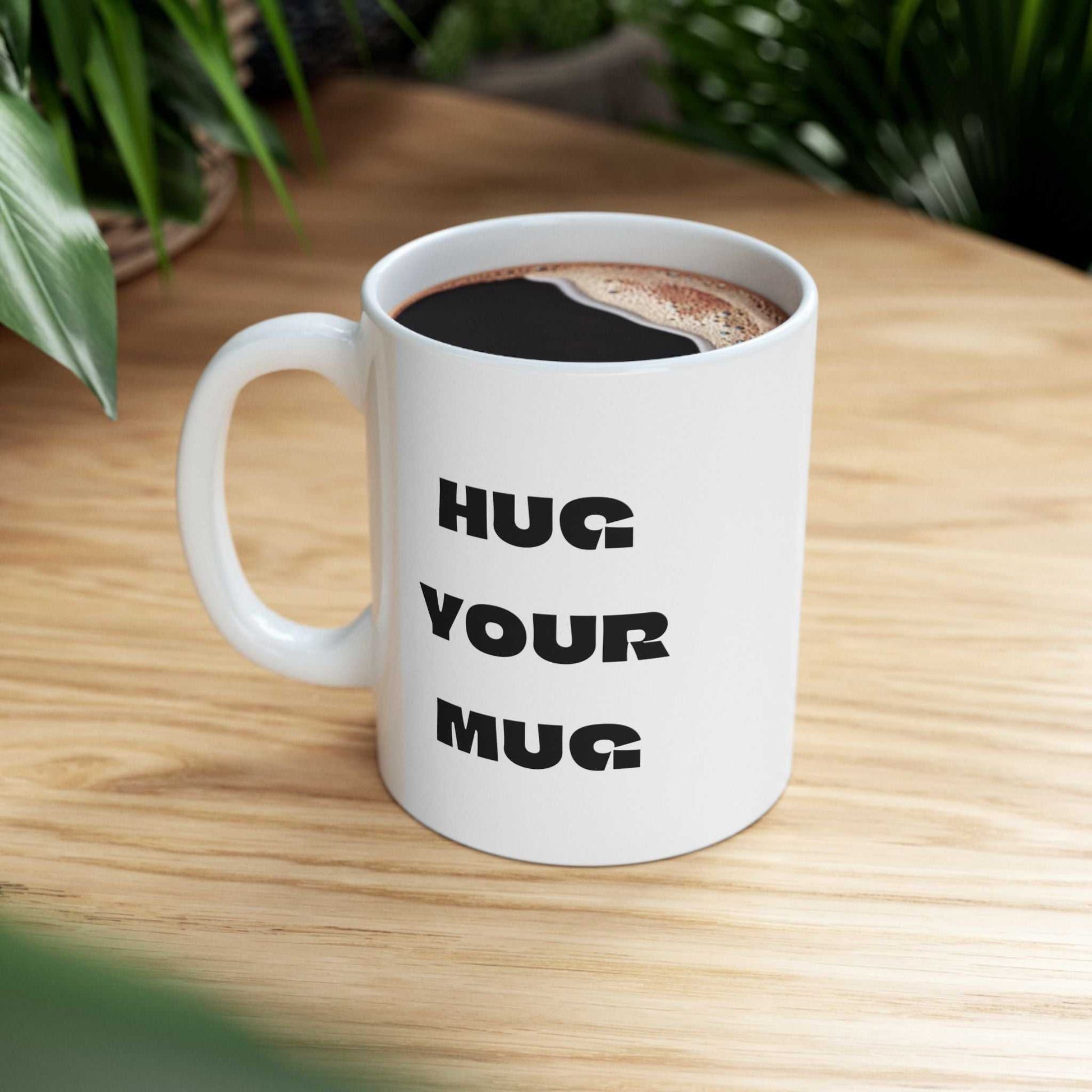 White mug with 'HUG YOUR MUG' text on a wooden surface
