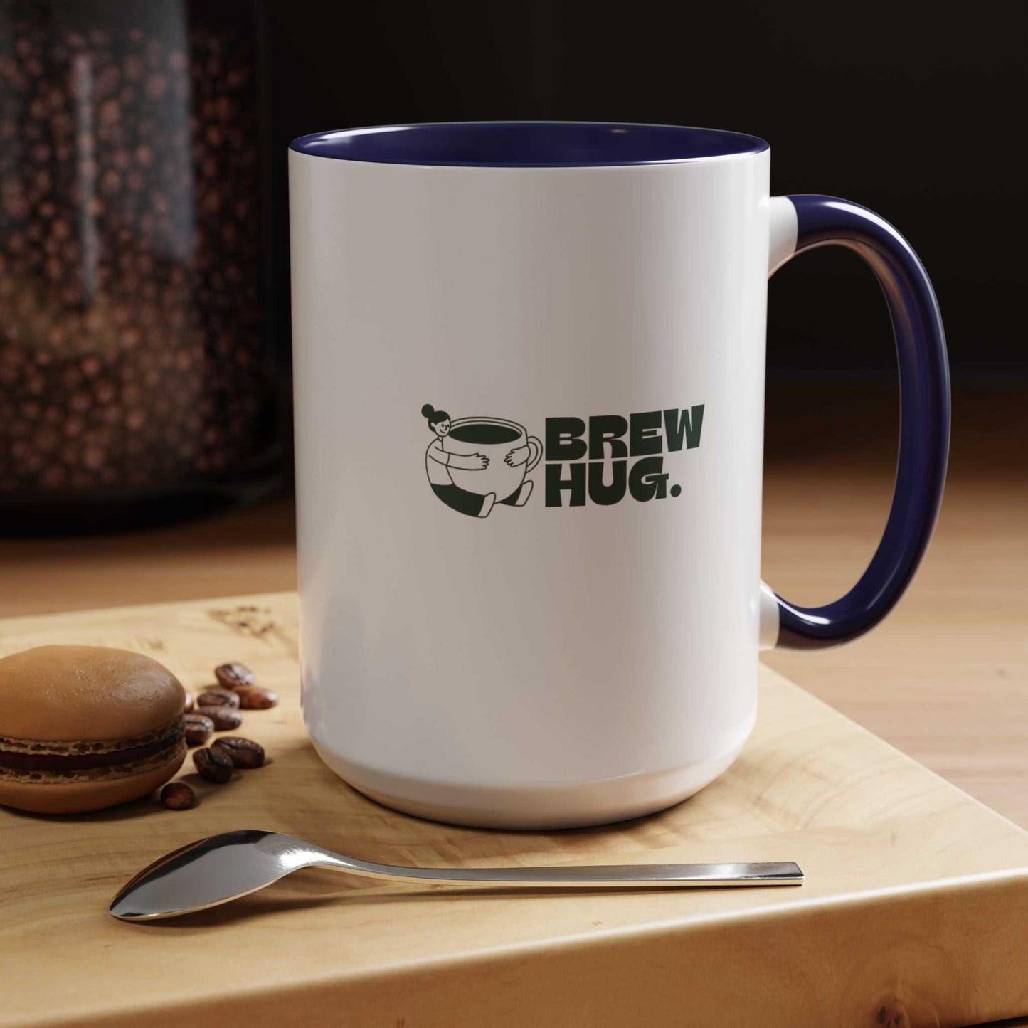 White mug with blue interior and handle, featuring 'Brew Hug' text and coffee bean graphic, on a wooden surface with coffee beans and a spoon.