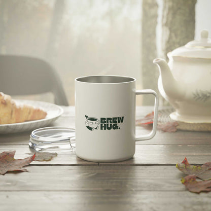 White mug with 'Brew Hug' text on a wooden table with a teapot and bread in the background.