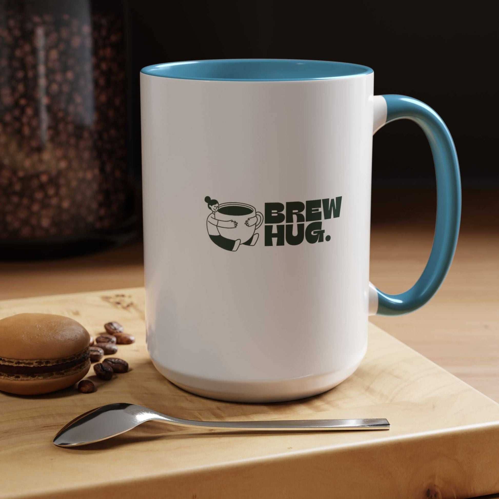 White mug with blue interior and handle, featuring 'Brew Hug' text, on a wooden surface with coffee beans and a spoon.